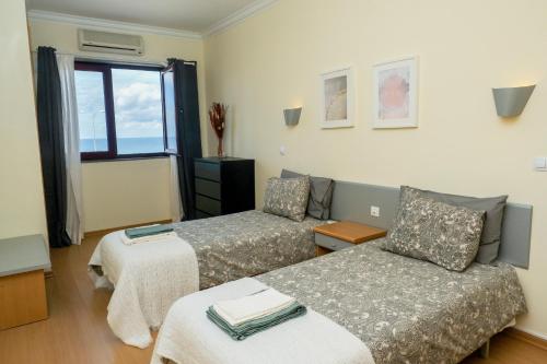 a room with two beds and a couch and a window at The Family Apart Beach in Ericeira