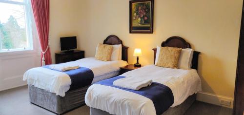 ein Hotelzimmer mit 2 Betten und einem TV in der Unterkunft Hartfell Guest House in Moffat