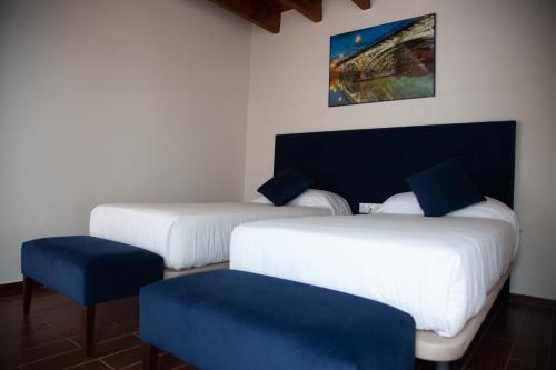 a room with two beds and a blue chair at Noches en Triana in Seville