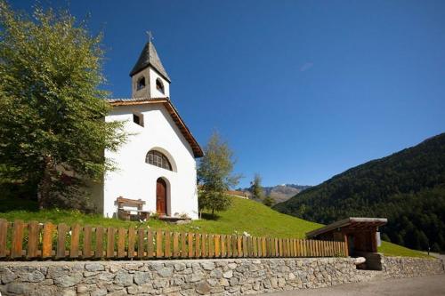 a small white church on a hill with a fence at Rieglhof Apartment Maisel in Caprone