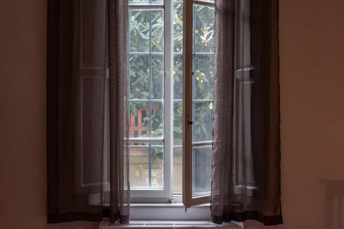 an open window with curtains in a room at Conce Apartment in Pisa