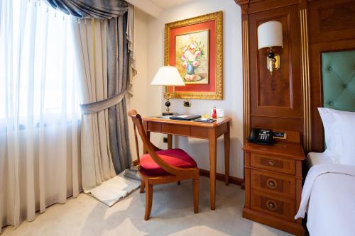 a bedroom with a bed, desk, chair and lamp at Swiss Diamond Hotel Prishtina in Prishtinë