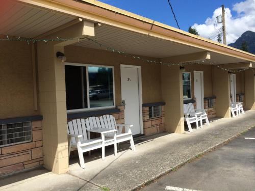 three white benches sitting outside of a building at City Centre Motel older building in Hope