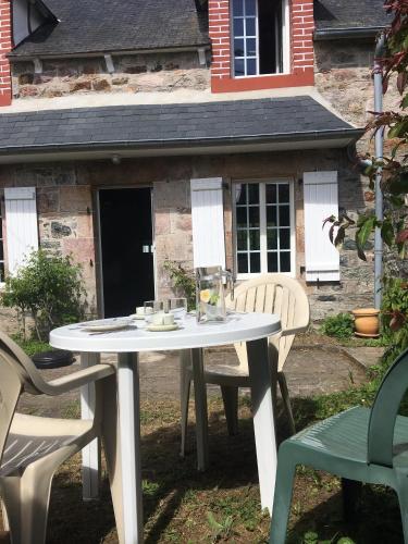 une table et des chaises blanches devant une maison dans l'établissement Maison dans la prairie, à Plurien