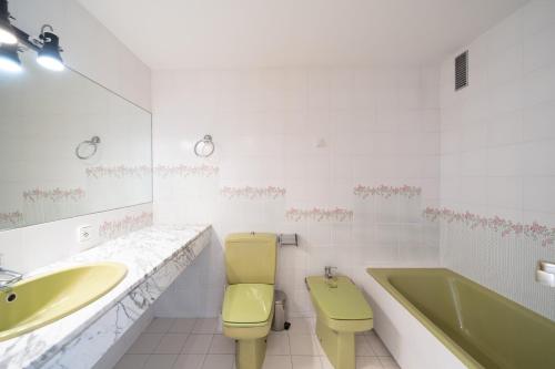 a bathroom with a yellow toilet and a sink and a tub at Apartament Greta in L'Escala
