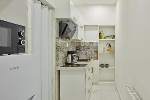 a white kitchen with a sink and a microwave at Helen Homestay Žižkov in Prague