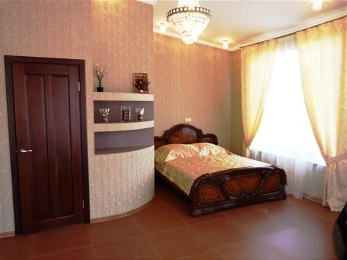 a bedroom with a bed and a window and a chandelier at Hotel Eliziy in Aramil'