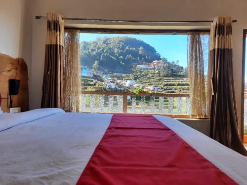 a bedroom with a large window with a view at Sunset Valley Holiday Inn in Ooty