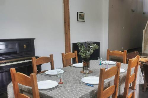 a dining room with a table and a piano at Longère rénovée avec accès direct à la mer in Guimaëc