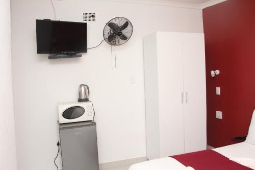 a bedroom with a bed and a tv on the wall at The White House Lodge in Cape Town