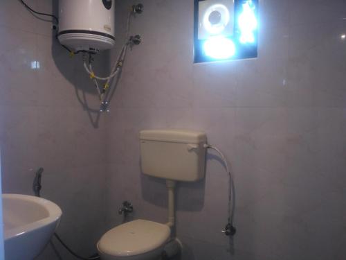 a bathroom with a toilet and a light on the wall at The Meadows in Kodaikānāl