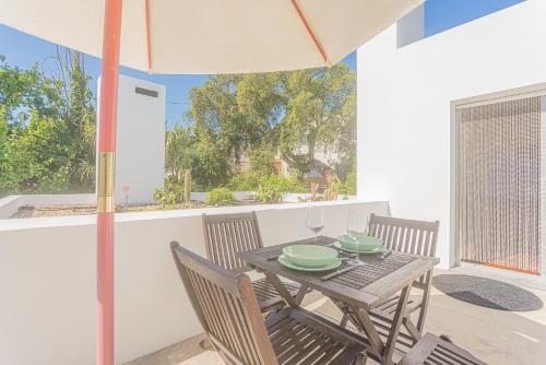 a table with two chairs and an umbrella on a patio at Melro's Places in Sesimbra