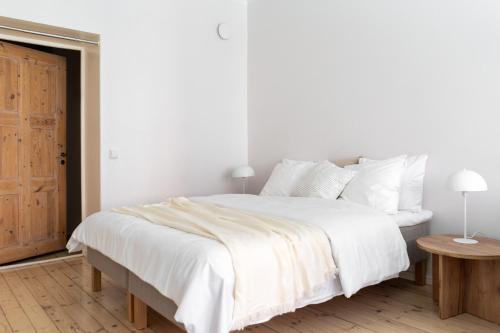 a white bedroom with a white bed and a wooden floor at Yksiö rauhallisella ja keskeisellä sijainnilla in Helsinki