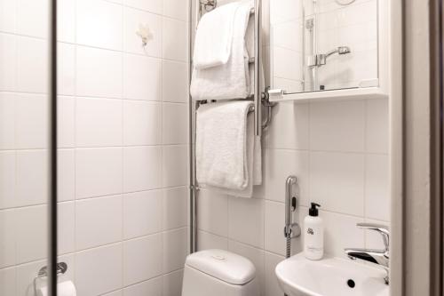 a white bathroom with a toilet and a sink at Yksiö rauhallisella ja keskeisellä sijainnilla in Helsinki