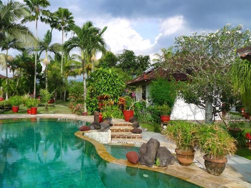 a swimming pool in a yard with trees and plants at Cabé Bali in Jasri