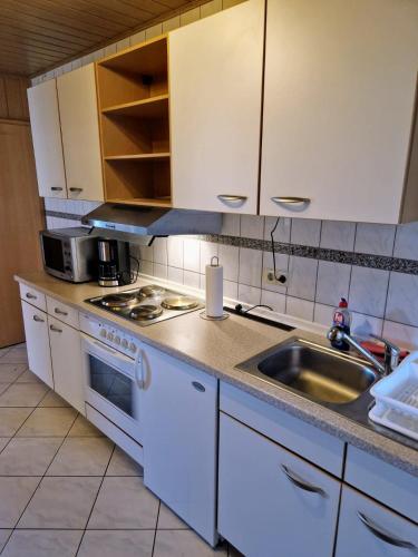 a kitchen with white cabinets and a sink at Idylle pur in der Nähe der Autostadt in Oebisfelde