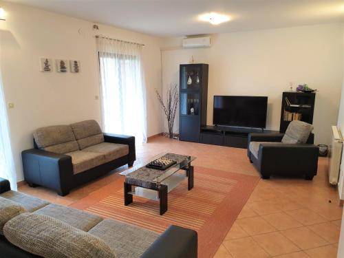a living room with two couches and a tv at Holiday home Elis in Fažana