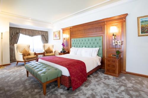 a hotel room with a large bed and chairs at Swiss Diamond Hotel Prishtina in Pristina