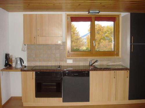 eine Küche mit einer Spüle, einem Herd und einem Fenster in der Unterkunft Chalet Lucille in Leysin