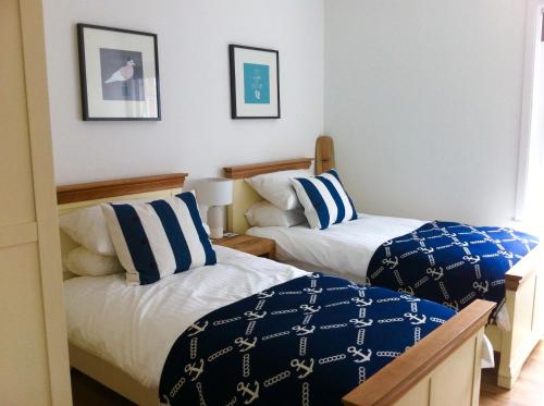 a bedroom with two beds with blue and white pillows at Harbour Retreat Padstow - Entire Apartment in the beautiful old town of Padstow Harbour in Padstow