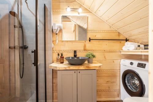 a bathroom with a sink and a washing machine at Wierchowe Domki z jacuzzi in Kościelisko