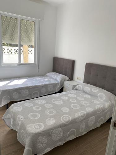 two twin beds in a room with two windows at Casa con Piscina cerca de la playa in Baiona