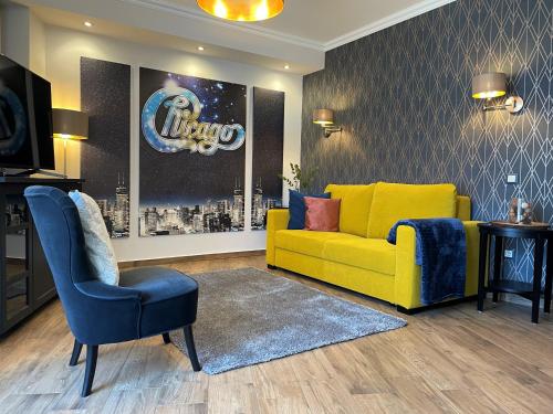 a living room with a yellow couch and a chair at Chicago Vendégház in Szentes
