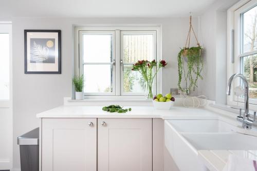 a white kitchen with white cabinets and a sink at Beach Cottage in St. Agnes