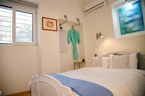 a bedroom with a white bed and a green shirt hanging on the wall at Aroura Homes Garden House 2BR 2BA Free Parking in Athens