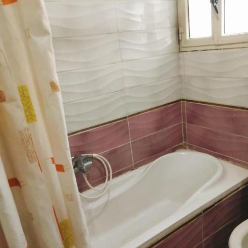 a small bathroom with a tub and a window at Elredy's apartments the blue edition in Cairo