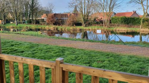 a wooden fence next to a body of water at Camping Les Sources Liencourt in Liencourt