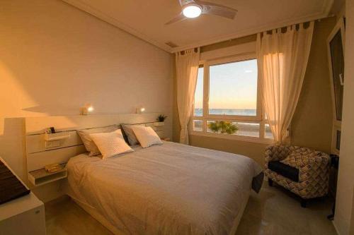 a bedroom with a large bed and a large window at Preciado apartamento con vistas frontales al mar in Cádiz