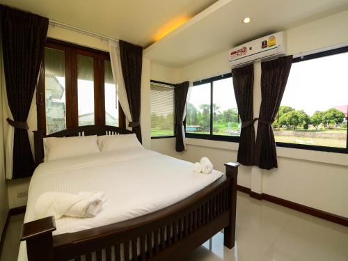 een slaapkamer met een bed met witte lakens en ramen bij Ban U Thong Accommodations in Phra Nakhon Si Ayutthaya