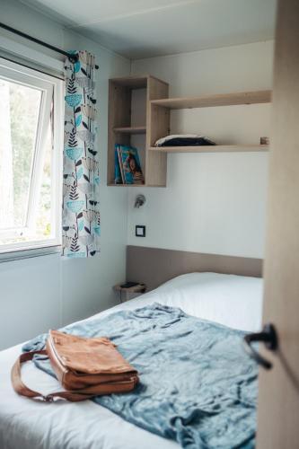 une chambre avec un lit et une fenêtre dans l'établissement Mobil Home XXL 4 chambres - Camping Le Coiroux, à Aubazines