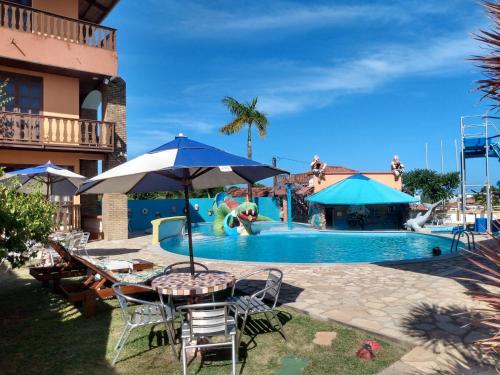 a pool at a resort with a table and chairs at Hotel Pousada Viking in Jacumã