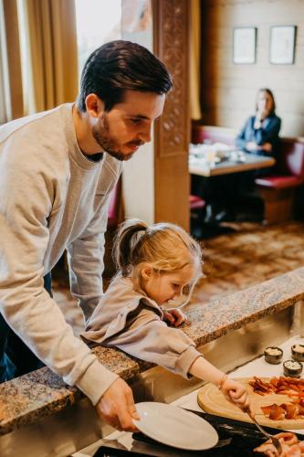 a man and a little girl at a table at Basekamp Mountain Budget Hotel in Katschberghöhe