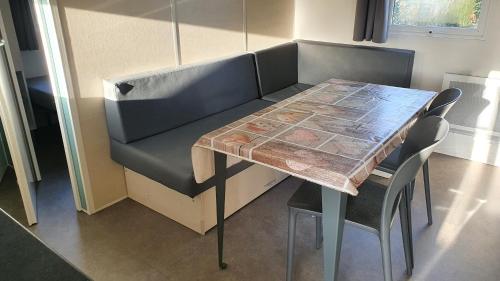 un tavolo con sedie e un divano in una camera di Camping Les Sources Liencourt a Liencourt