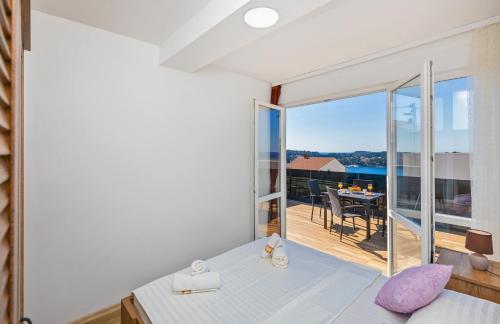 1 Schlafzimmer mit einem Bett und einem Balkon mit einem Tisch in der Unterkunft Apartments Sweet and Cozy in Cavtat