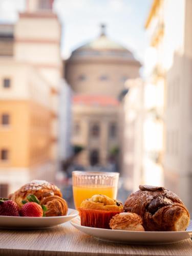 two plates of pastries on a table with a glass of orange juice at DhOME B&B in Palermo