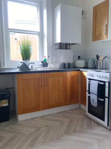 a kitchen with wooden cabinets and a sink and a stove at The Chine Stylish Studio Near Beach Free Parking Sleeps Max 4 Pet Friendly in Bournemouth