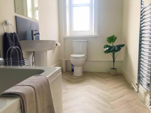 a bathroom with a sink and a toilet and a window at The Chine- A Spacious Studio Close to the Beach in Bournemouth