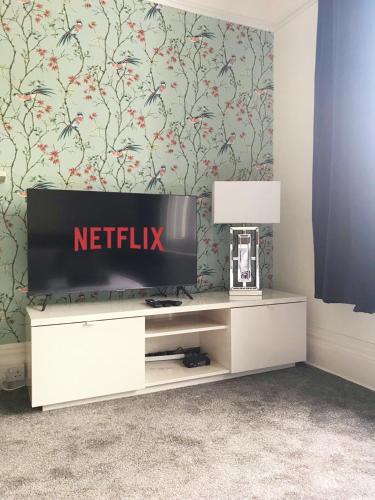 a living room with a television on a white cabinet at The Chine Stylish Studio Near Beach Free Parking Sleeps Max 4 Pet Friendly in Bournemouth
