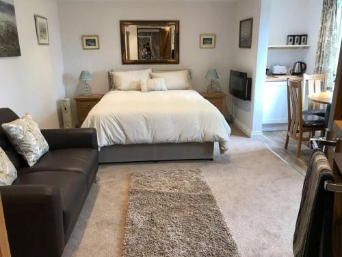 a bedroom with a bed and a couch and a mirror at Lovely detached garden chalet in Broadstone