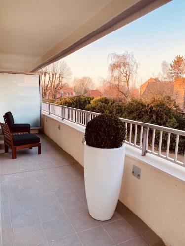 un grand pot blanc sur un balcon avec une chaise dans l'établissement Clos de Bénédicte Appart, à Marcq-en-Barœul
