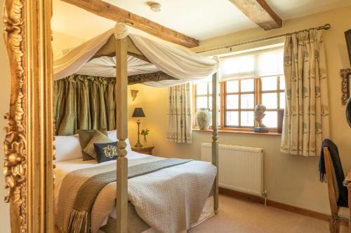 a bedroom with a canopy bed and a window at Blounts Court Farm in Devizes