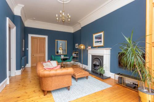 South Learmonth Gardens Apartment في إدنبرة: غرفة معيشة مع جدران زرقاء وأريكة ومدفأة
