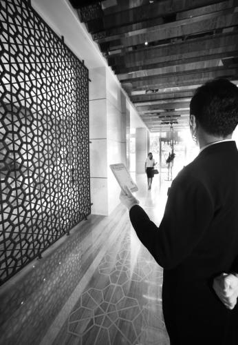 a woman is holding a book in a hallway at The Grove Suites by Grand Aston in Jakarta