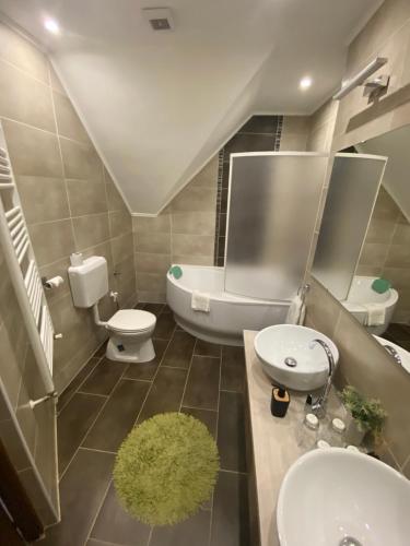 a bathroom with a sink and a toilet and a tub at Babylon Pizzéria Vendégház in Miskolc