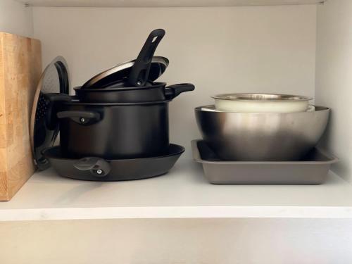 three pots and pans on a shelf in a kitchen at Robert's White Apartament in Ploieşti