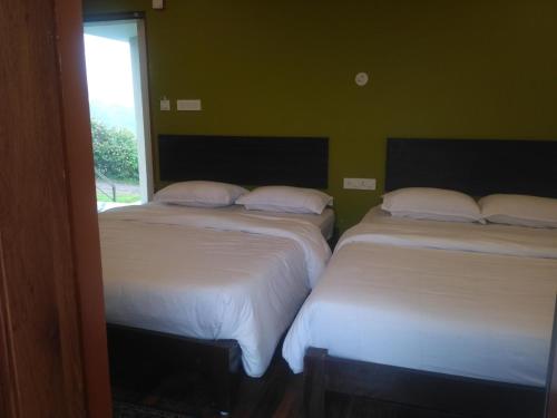 two beds in a room with a window at The Meadows in Kodaikānāl